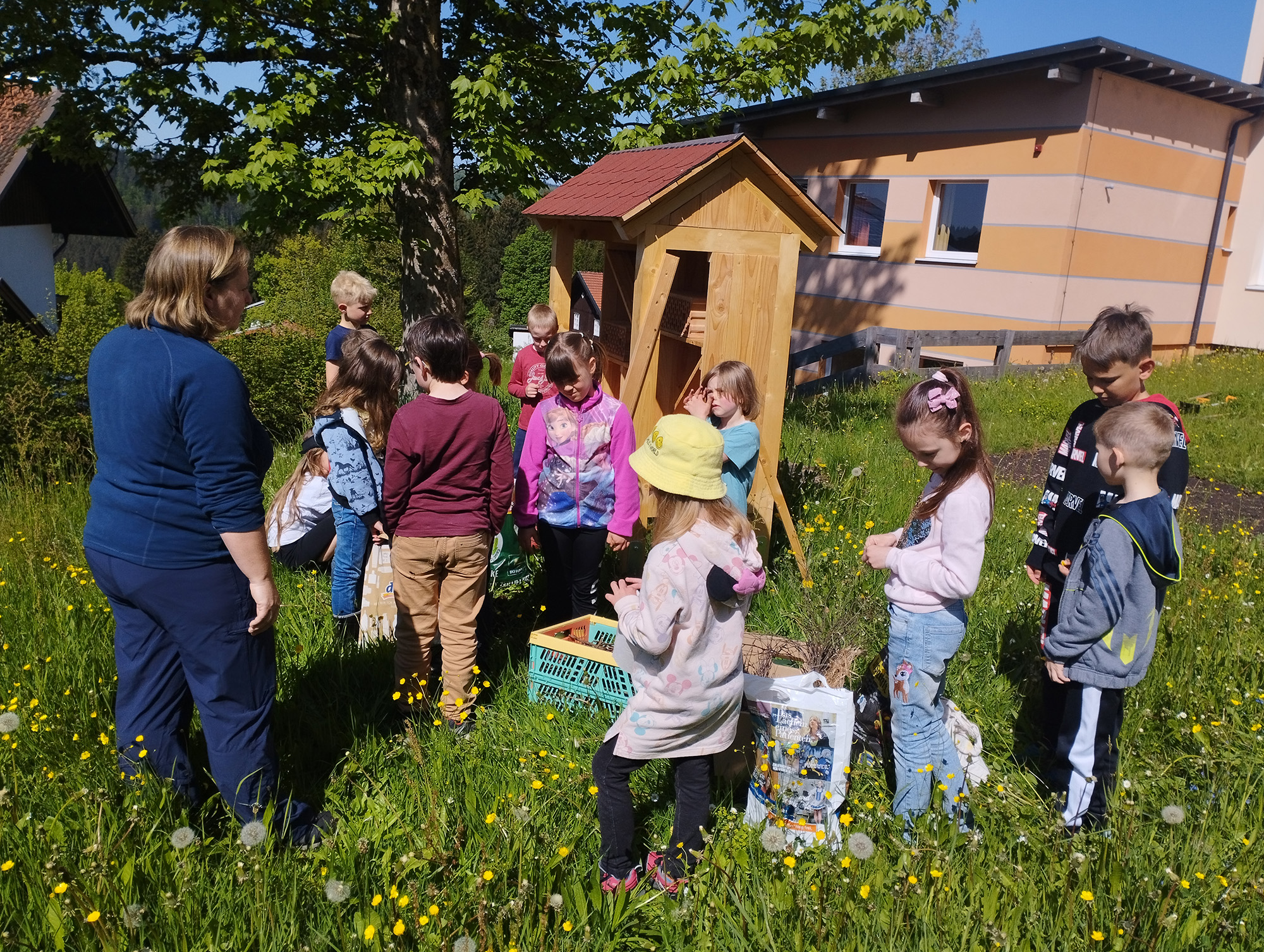 Zusammen mit der Nationalpark-Mitarbeiterin Nicole Graf-Kilger (l.) füllten die Kinder der Grundschule Mauth das Insektenhotel mit Zweigen und Schilf. (Foto: Grundschule Mauth)